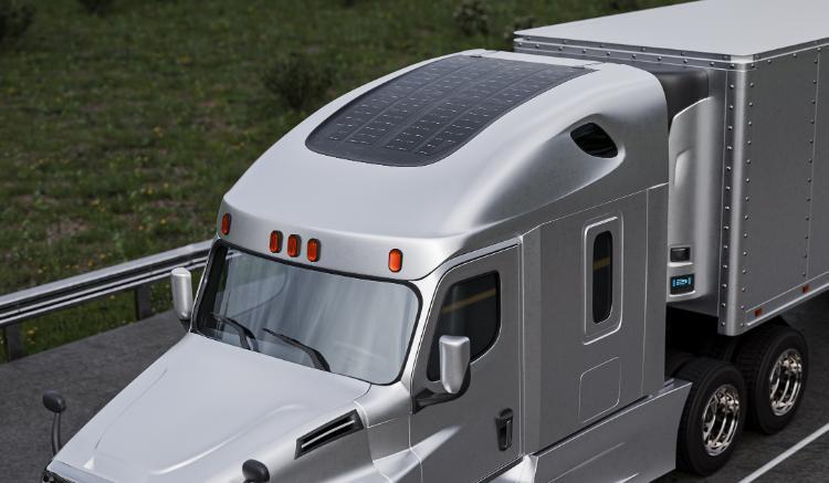 Close up of a silver Freightliner Cascadia truck driving down the road with a fairing integrated crystalline silicon solar panel.