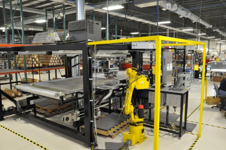 Yellow robotic equipment on a solar manufacturing floor.