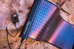 LightSaver Max Portable Solar Charger unrolled on an orange rock charging a GoPro