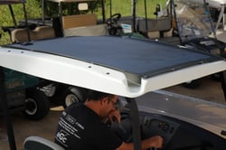 Man sitting in a golf cart with a solar panel installed on the top