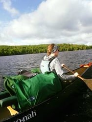 LightSaver Portable Solar Charger on canoe with woman paddling