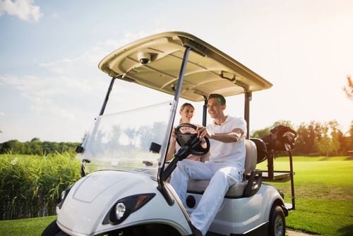 man and woman driving a golf car