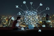 Man sitting on top of a building on computer with a graphic of connected IoT devices