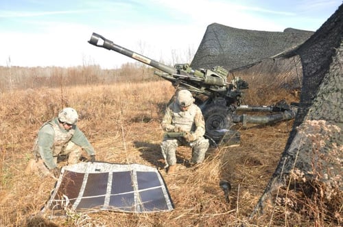 soldiers unfolding a solar panel in a field